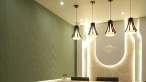 A reception area with a marble counter, a green textured wall, a black and white patterned floor, and a beige sofa. - Serenity By The Ganges (Haridwar)