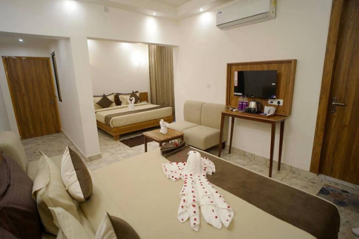 Una habitación de hotel con cama, sofá, televisor y mesa de centro.