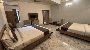A hotel room with two beds, a television, a ceiling fan, and a marble floor. - Serenity By The Ganges (Haridwar)
