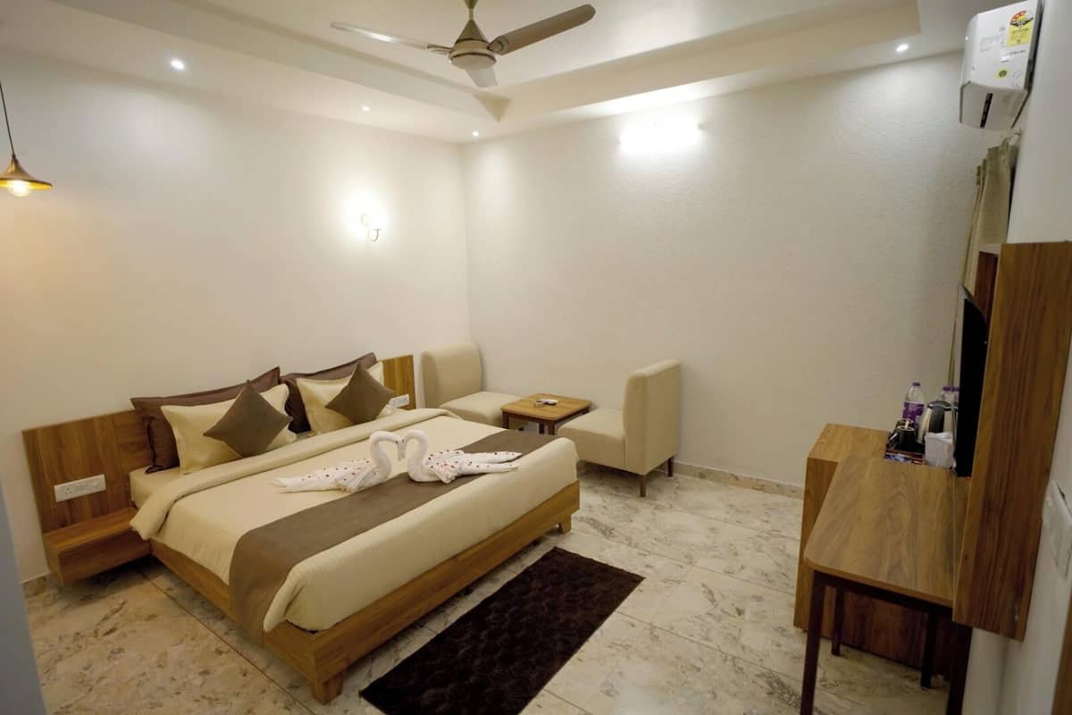 Habitación de hotel con cama, mesita de noche, silla y escritorio con una silla.