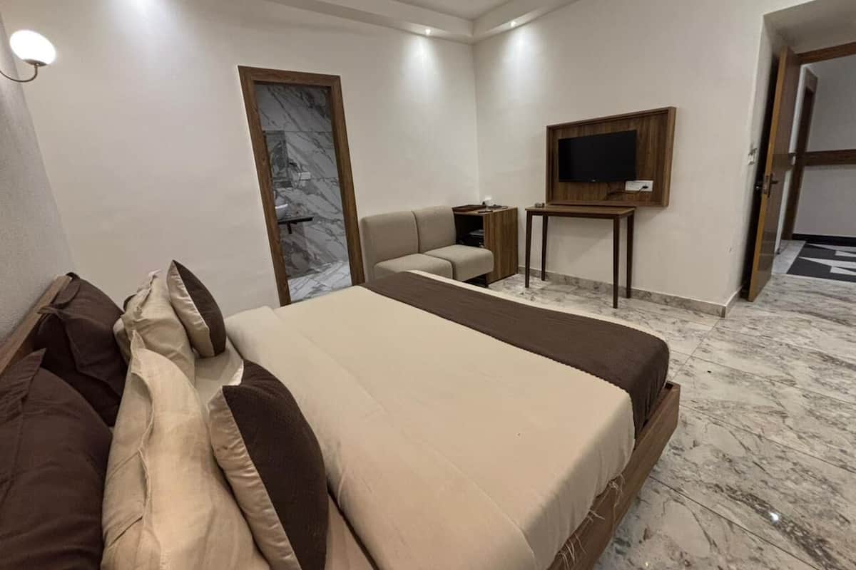 Una habitación de hotel con una cama grande, televisión, una mesita y un sofá.