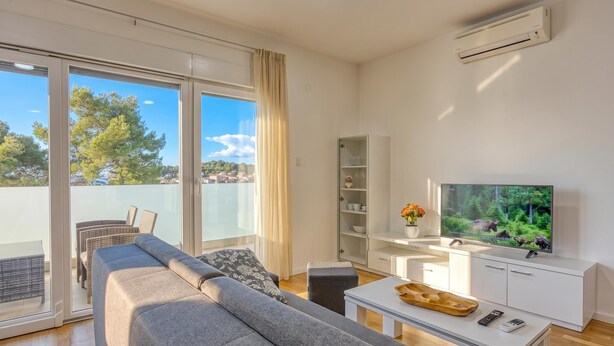 Ein modernes Wohnzimmer mit einer Couch, einem Fernseher und einem Balkon mit Blick.