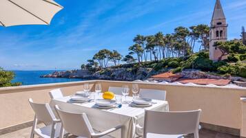 A table set for dining with a view of the sea and a church in the background.