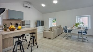 A modern kitchen with a wooden countertop, bar stools, and a dining area with a table and chairs. - The View Apartment Veli Losinj (Mali Losinj)