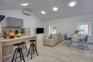 Una cucina moderna con isola centrale, zona pranzo con tavolo e sedie, un divano e una TV.