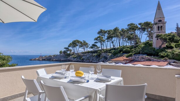 A table set for dining with a view of the sea and a church tower. - The View Apartment Veli Losinj (Mali Losinj)