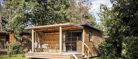 A wooden cabin with a porch, outdoor seating, and a staircase leading to the entrance.