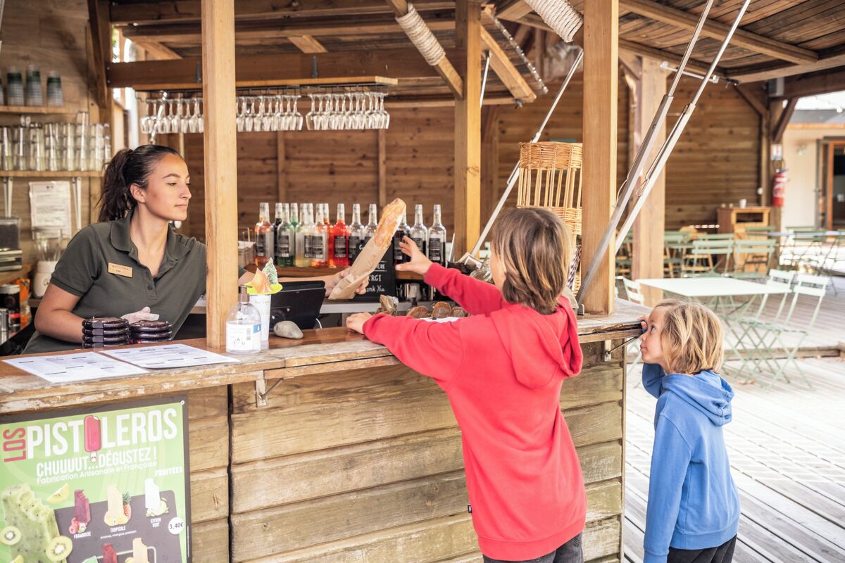 Ein hölzerner Außenbereich mit Bar, Flaschen und Gläsern.