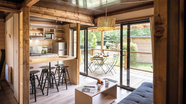 Een moderne keuken met houten balken, een eethoek met een tafel en stoelen, en een grote schuifdeur die uitkomt op een terras.