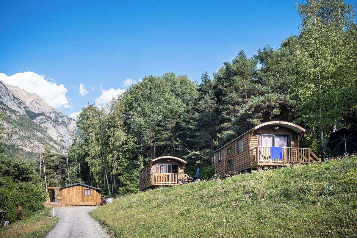 A wooden cabin with a balcony, surrounded by trees and mountains.