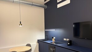 A modern kitchen with a built-in microwave, a large flat-screen TV, and a dining area with a round table and chairs.
