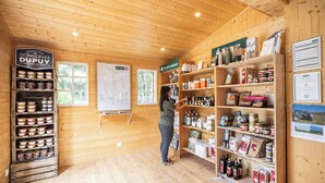 A rustic wooden interior with shelves stocked with food items and a person organizing them. - Huttopia Oléron les Chênes Verts  (Dolus-d'Oléron)