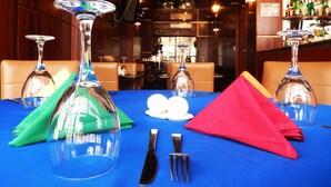 A restaurant setting with tables set for dining, featuring clear glassware and a blue tablecloth.