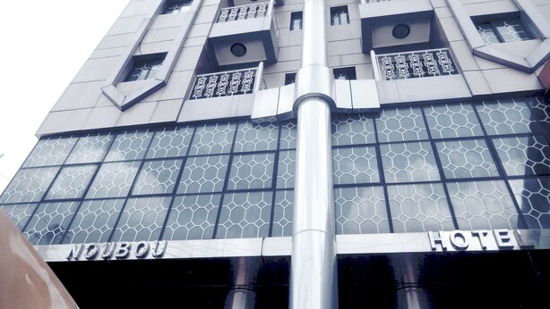 A hotel with a modern design, featuring a prominent central column, patterned windows, and balconies with intricate railings.