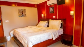 Habitación de hotel con una cama grande, una mesita de noche, aire acondicionado de pared y un cuadro en la pared.