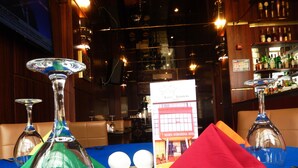 A table set with two wine glasses, a green napkin, a red napkin, and a menu at the Noubaou International Hotel.