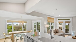 Una cocina moderna con una isla grande, un comedor con sillas y vistas a zonas verdes.