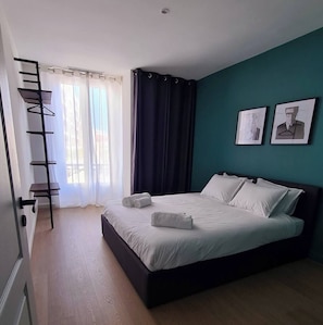 A bedroom with a bed, a window with curtains, a wall-mounted shelf, and two framed pictures. - Lovely 2-bedroom apartment in Cannes 5mn walk to Croisette (Cannes)
