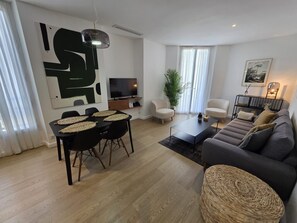 A modern living room with a dining area, a sofa set, a television, and a large abstract painting. - Lovely 2-bedroom apartment in Cannes 5mn walk to Croisette (Cannes)