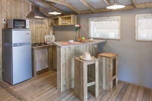 Una cocina compacta con paredes de madera y una isla central, equipada con refrigerador, microondas y estufa.
