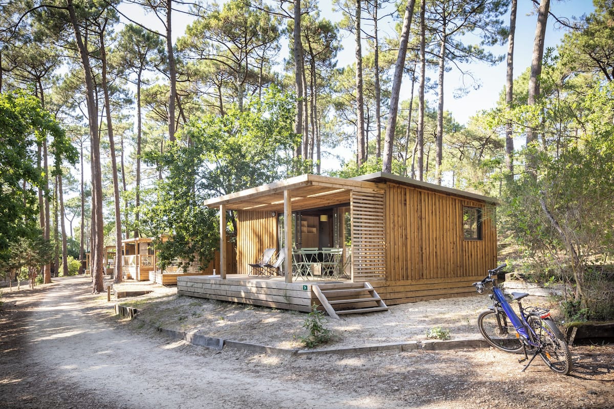 Une cabane en bois avec une véranda, une table et un vélo.