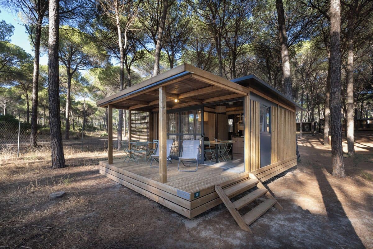 Une petite cabane en bois dotée d’une terrasse, entourée d’arbres.