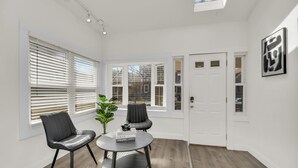 A modern room with a skylight, two black chairs, a round table with a Vogue magazine, and a door with frosted glass panels. - Stylish & Comfy Stay: Close to Downtown (Chicago)