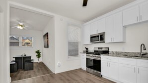 A modern kitchen with white cabinets, stainless steel appliances, and a wooden floor. - Stylish & Comfy Stay: Close to Downtown (Chicago)