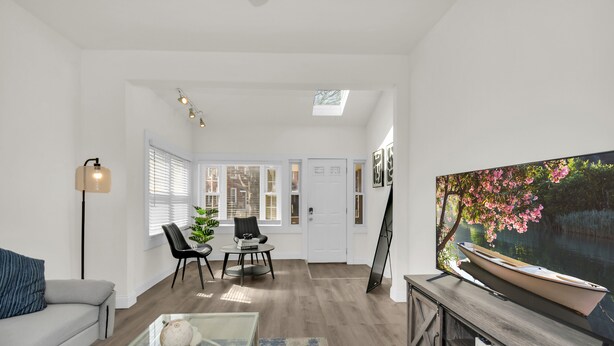 A spacious living area with a large flat-screen TV, a dining table with chairs, a sofa, and a floor lamp. - Stylish & Comfy Stay: Close to Downtown (Chicago)