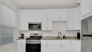 A modern kitchen with white cabinets, stainless steel appliances, and granite countertops. - Stylish & Comfy Stay: Close to Downtown (Chicago)