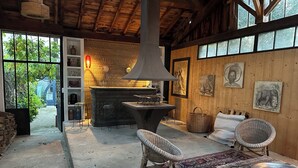 Un interior rústico con chimenea de piedra, mobiliario de mimbre y obras de arte en las paredes.