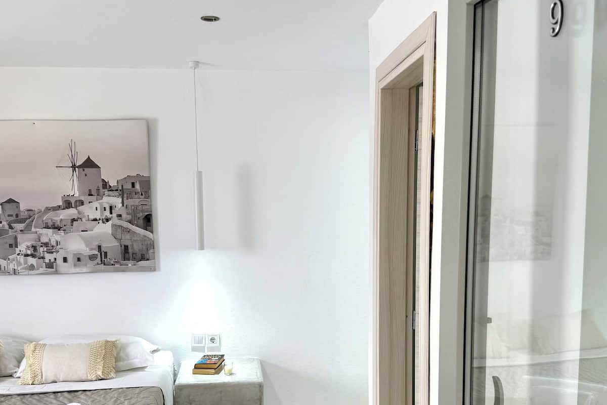 A modern hotel room with a bed, bedside table, and a wardrobe.