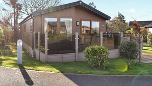 Una casa de madera de un piso con ventanas grandes y un patio cercado.