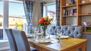 Un comedor con una mesa dispuesta para dos, una estantería y vistas al exterior.