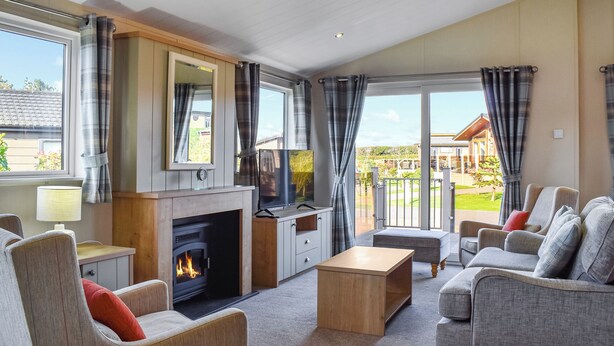 Un salón con chimenea, sofá, televisor y vistas al exterior.