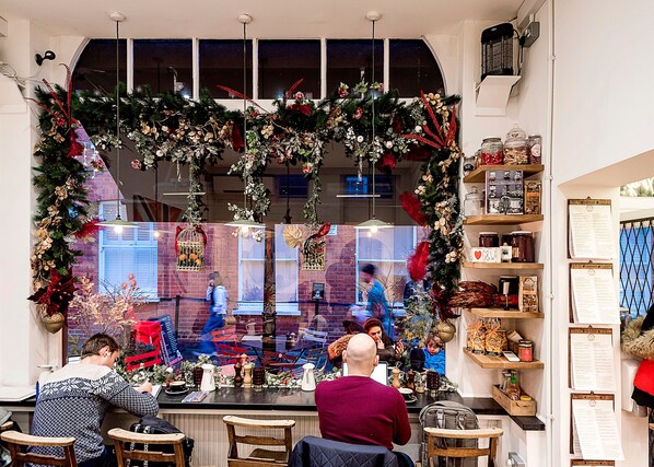 A restaurant with a festive Christmas decoration, a brick wall, and a menu board. - The King of Spades - by Out of Office Lifestyle (London)