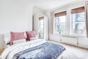 A bedroom with a bed, a wardrobe, and a window with curtains.