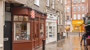 A storefront with a sign reading "EXCLUSIVO DESIGNER SECOND HAND STORE" and a black bollard in front. - The King of Spades - by Out of Office Lifestyle (London)