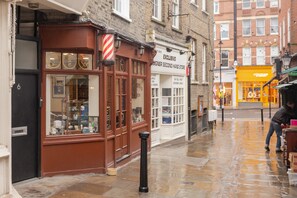 A storefront with a sign reading "EXCLUSIVO DESIGNER SECOND HAND STORE" and a black bollard in front. - The King of Spades - by Out of Office Lifestyle (London)