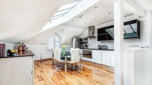 A modern kitchen with white cabinetry, a dining area with a table and chairs, and a skylight above. - The King of Spades - by Out of Office Lifestyle (London)