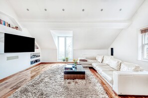 Una sala de estar moderna con un sofá blanco, una mesa de centro y un televisor de pantalla plana montado en la pared.