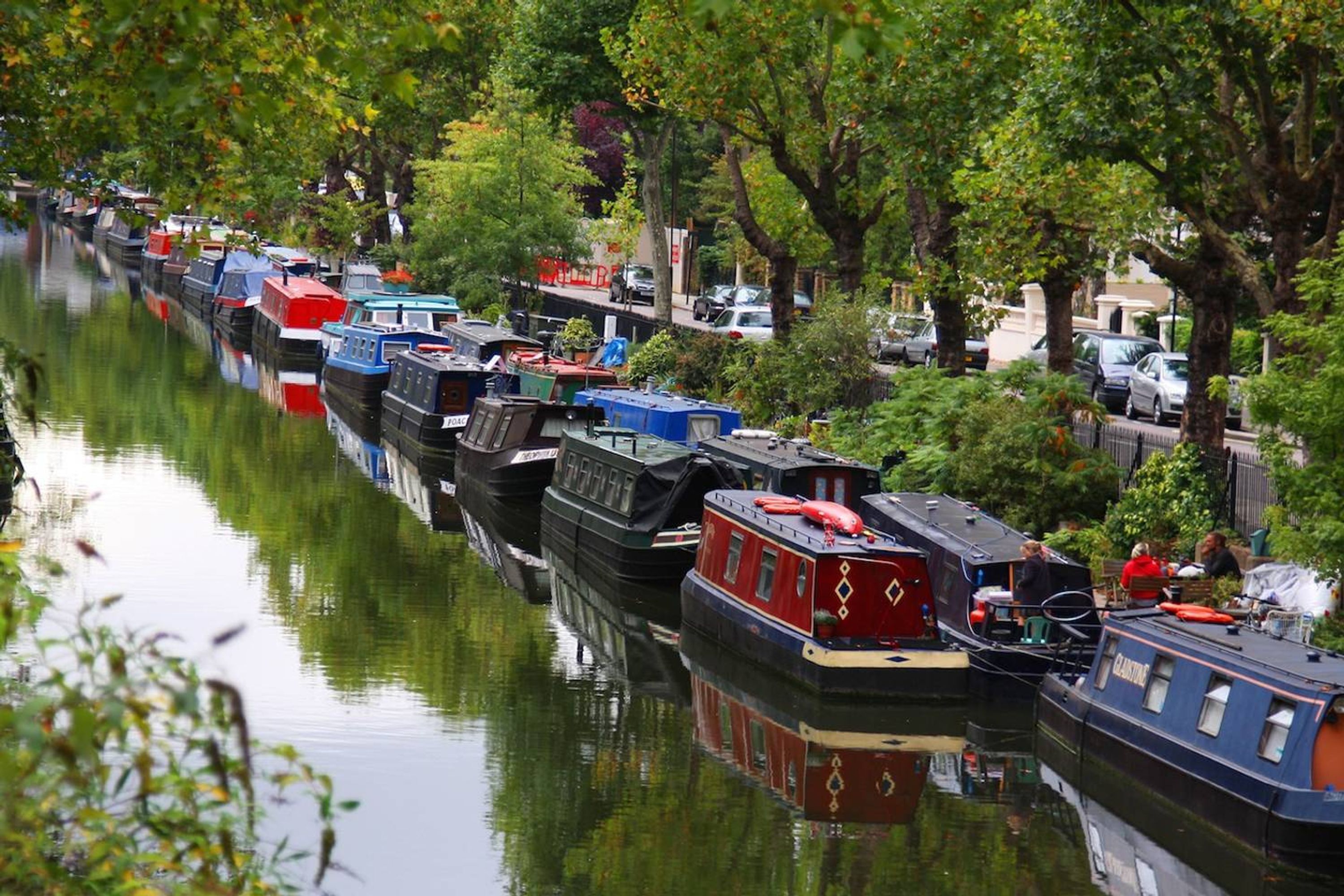 A canal lined with narrowboats docked along the water.