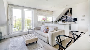 A modern living room with a sofa, ottoman, and dining area. - The Luxury Treehouse - One bed Little Venice - by Out of Office Lifestyle (London)