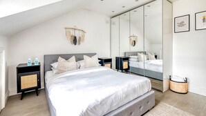 A modern bedroom with a large bed, a nightstand, a mirror, and a wall-mounted shelf. - The Luxury Treehouse - One bed Little Venice - by Out of Office Lifestyle (London)