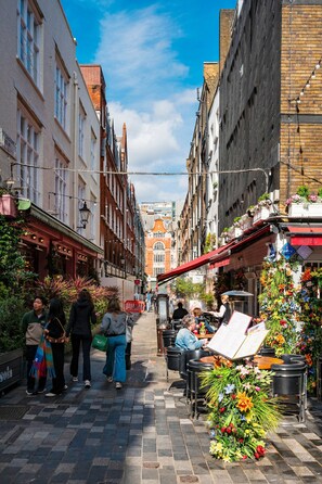 A narrow street lined with buildings, outdoor seating for cafes, and pedestrians. - The Nordic Nook Luxury Marylebone - by Out of Office Lifestyle (London)