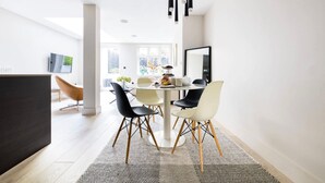 A modern dining area with a round table, black and white chairs, and a black pendant light. - The English Gentleman Hampstead Heath - by Out of Office Lifestyle (London)