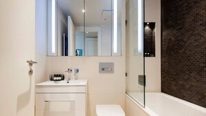 Ein modernes Badezimmer mit einem weißen Waschtisch, einer Toilette und einer Badewanne.