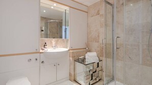 Ein modernes Badezimmer mit einer Duschkabine aus Glas, einem weißen Waschbecken und einem Waschtisch mit Glasplatte.