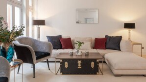 Ein stilvolles Wohnzimmer mit Sofa, Sessel und Couchtisch mit einem alten Koffer.