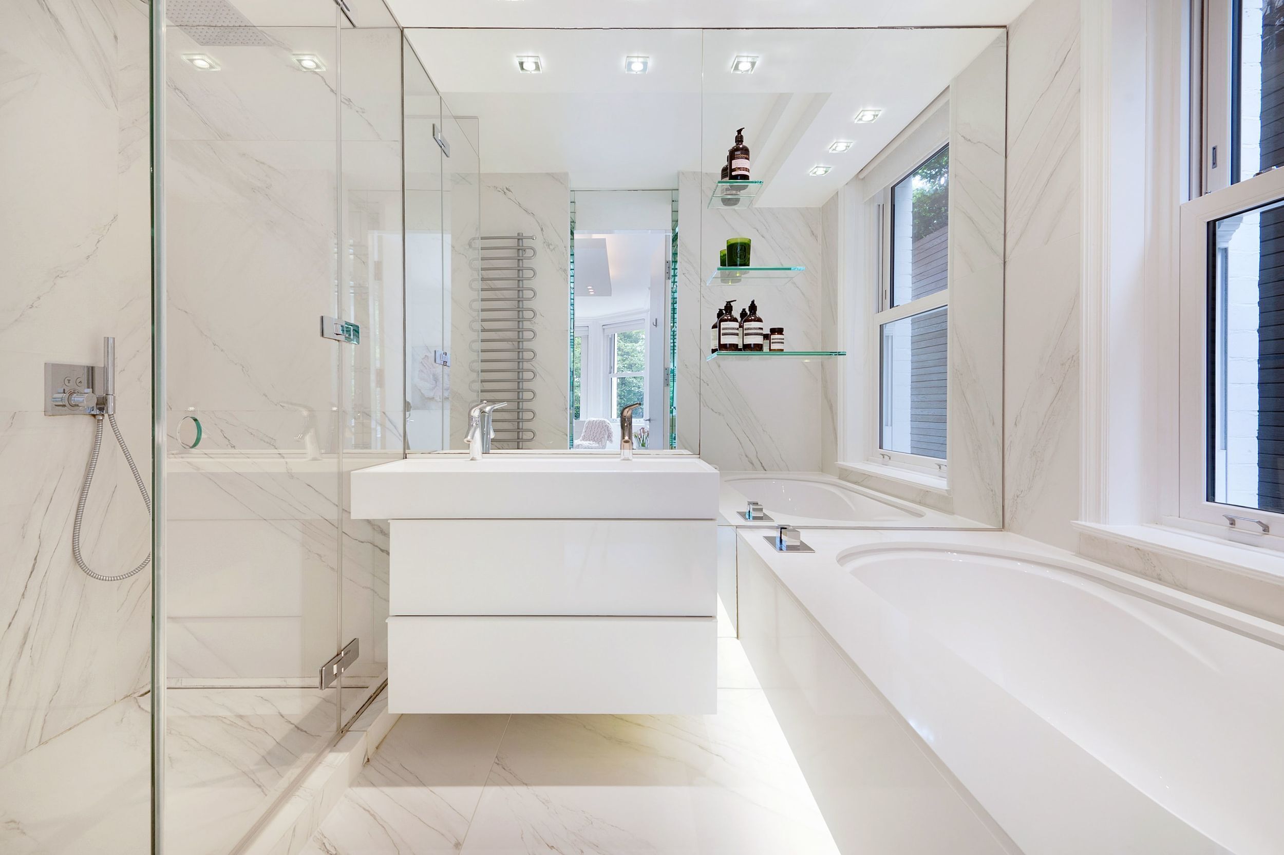 A modern bathroom with a glass shower enclosure, a white vanity with a large mirror, and a freestanding bathtub.